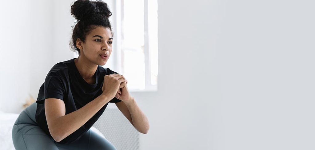 An African American woman performs a standing squat while wearing workout clothes