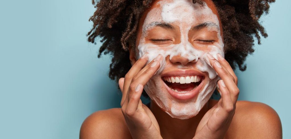 A woman scrubbing her face with a sudsy face wash