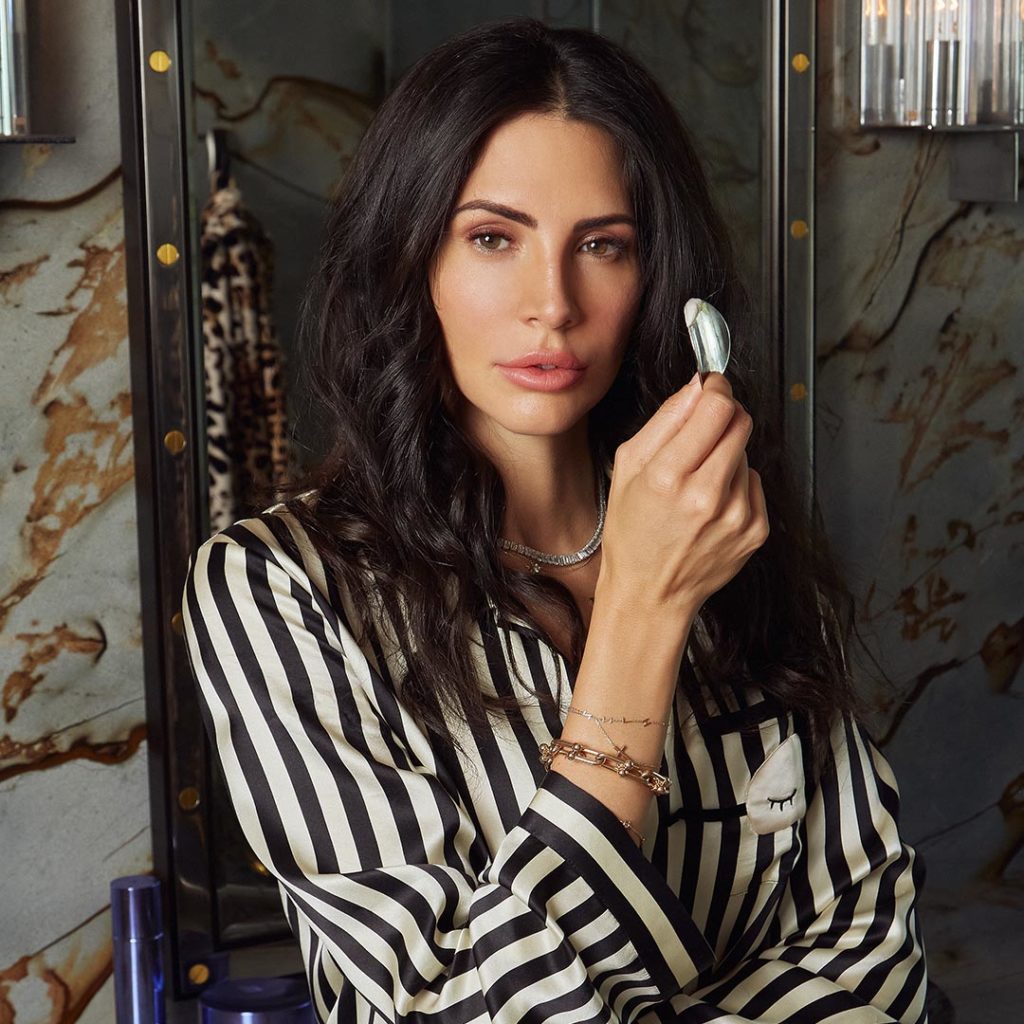 CEO Hope Dworaczyk in striped pajamas holds a MUTHA Body Butter container