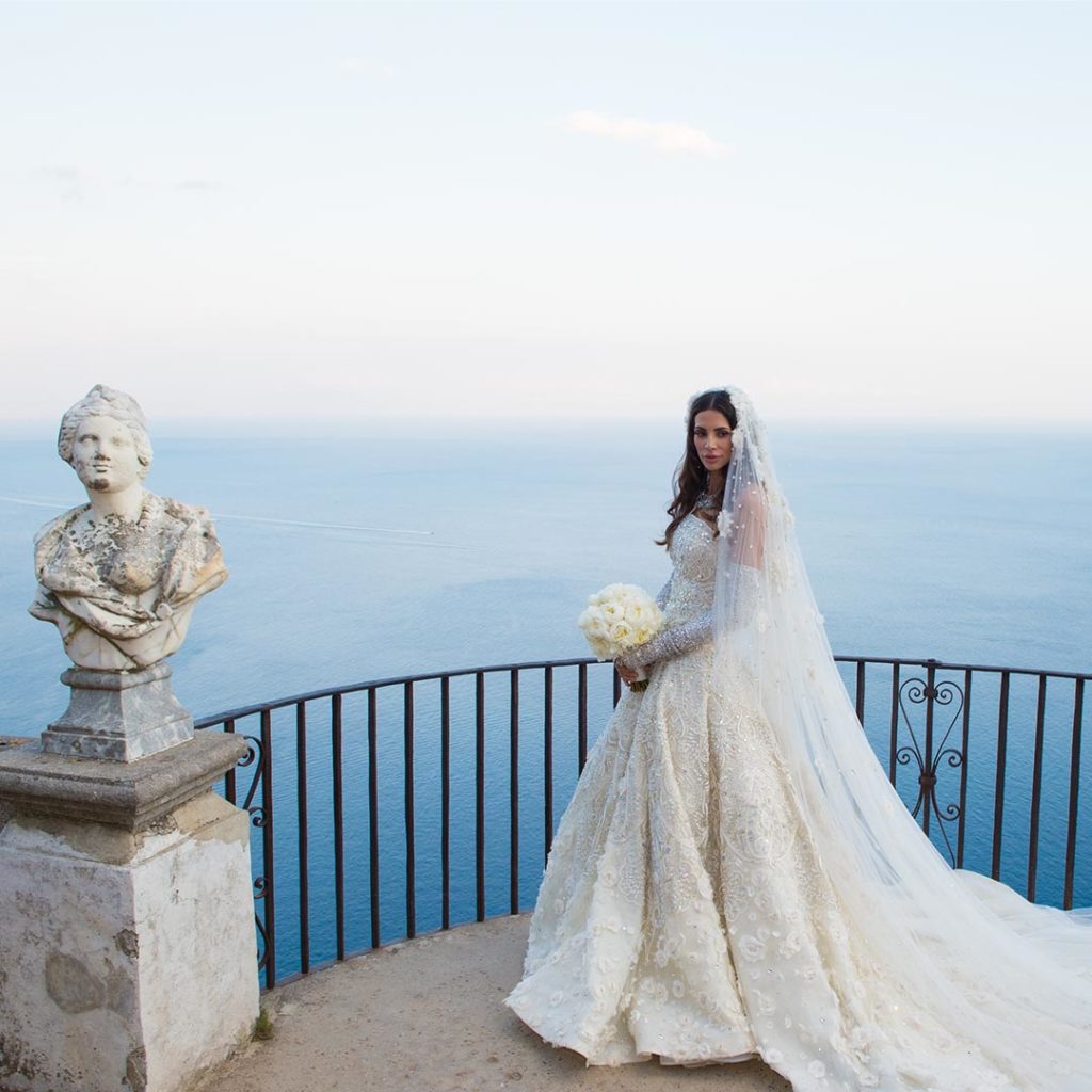 Hope Dworaczyk, pictured on her wedding day, stands on a balcony with the ocean in the background