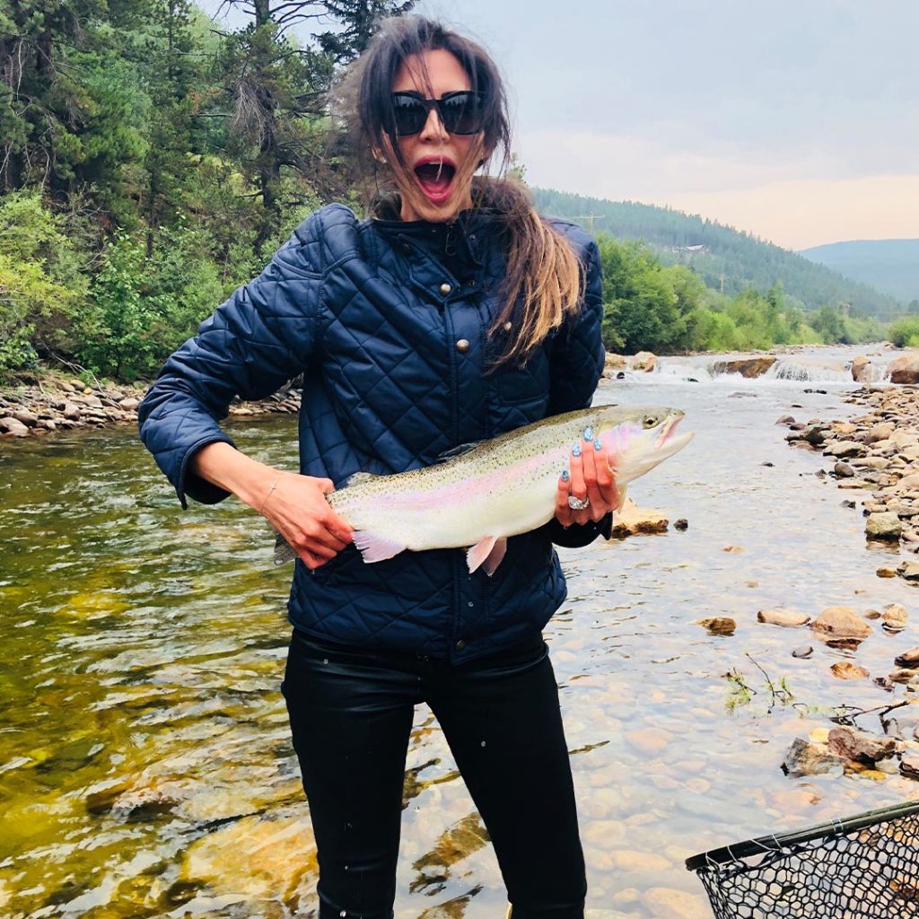 Hope Dworaczyk stands in a river and holds a fish in Colorado