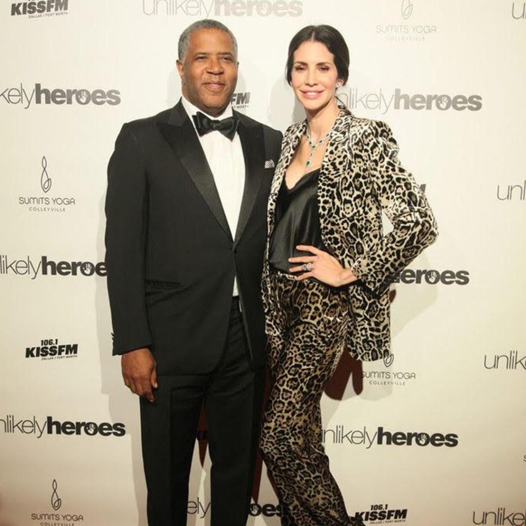 Hope Dworaczyk and Robert F. Smith smile on the red carpet for an Unlikely Heroes event