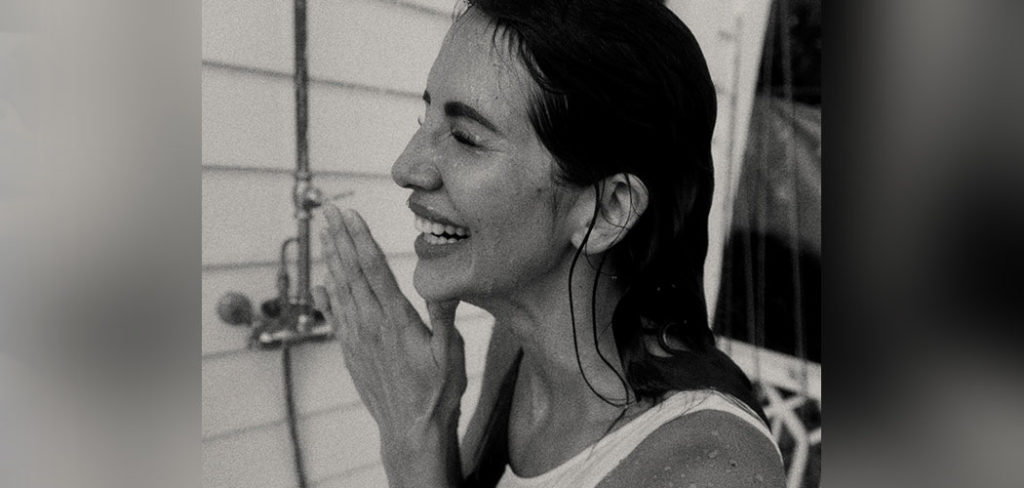 A black and white photo of Hope Dworaczyk Smith as she wears a bathing suit and laughs in the shower.