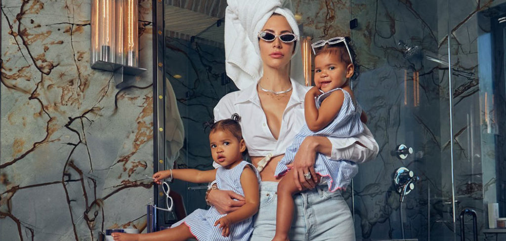 Hope and her daughters stand in a bathroom while wearing sunglasses and smiling.