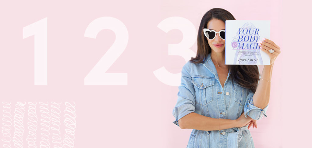 Hope stands holding her book while wearing heart-shaped sunglasses against a pink background with the numbers 1, 2, 3.