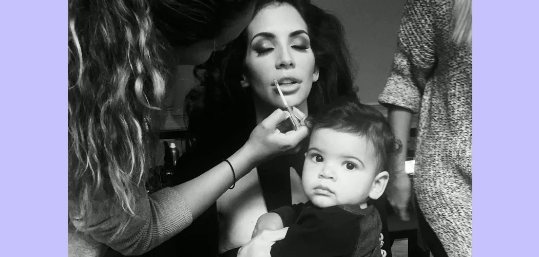 Hope Smith getting her makeup touched up by two women on either side of her while she holds her son.